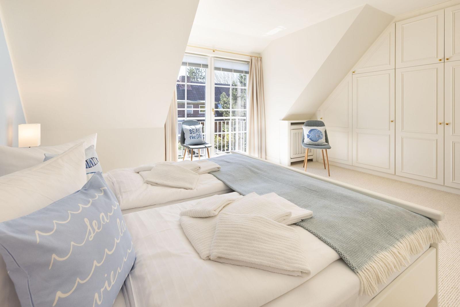 Schlafzimmer mit Doppelbett, Fenster und Kleiderschrank.