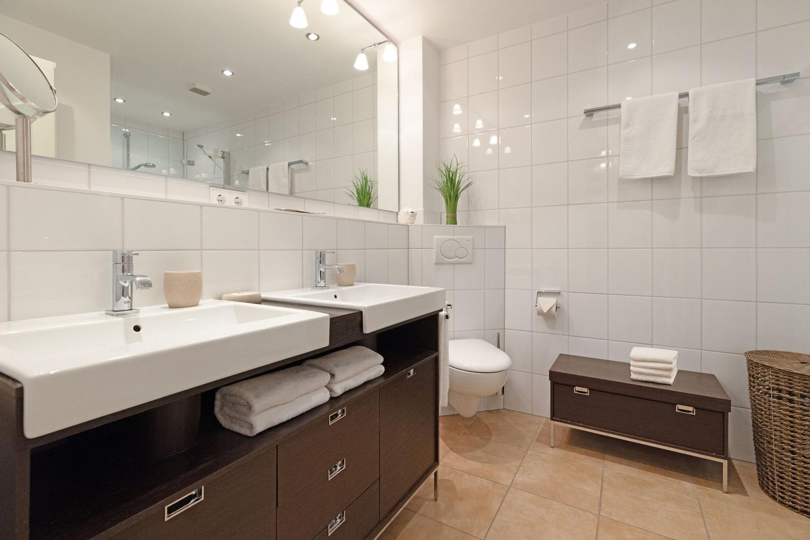 Badezimmer mit zwei Waschbecken, Spiegelschrank, Toilette und Badematten.