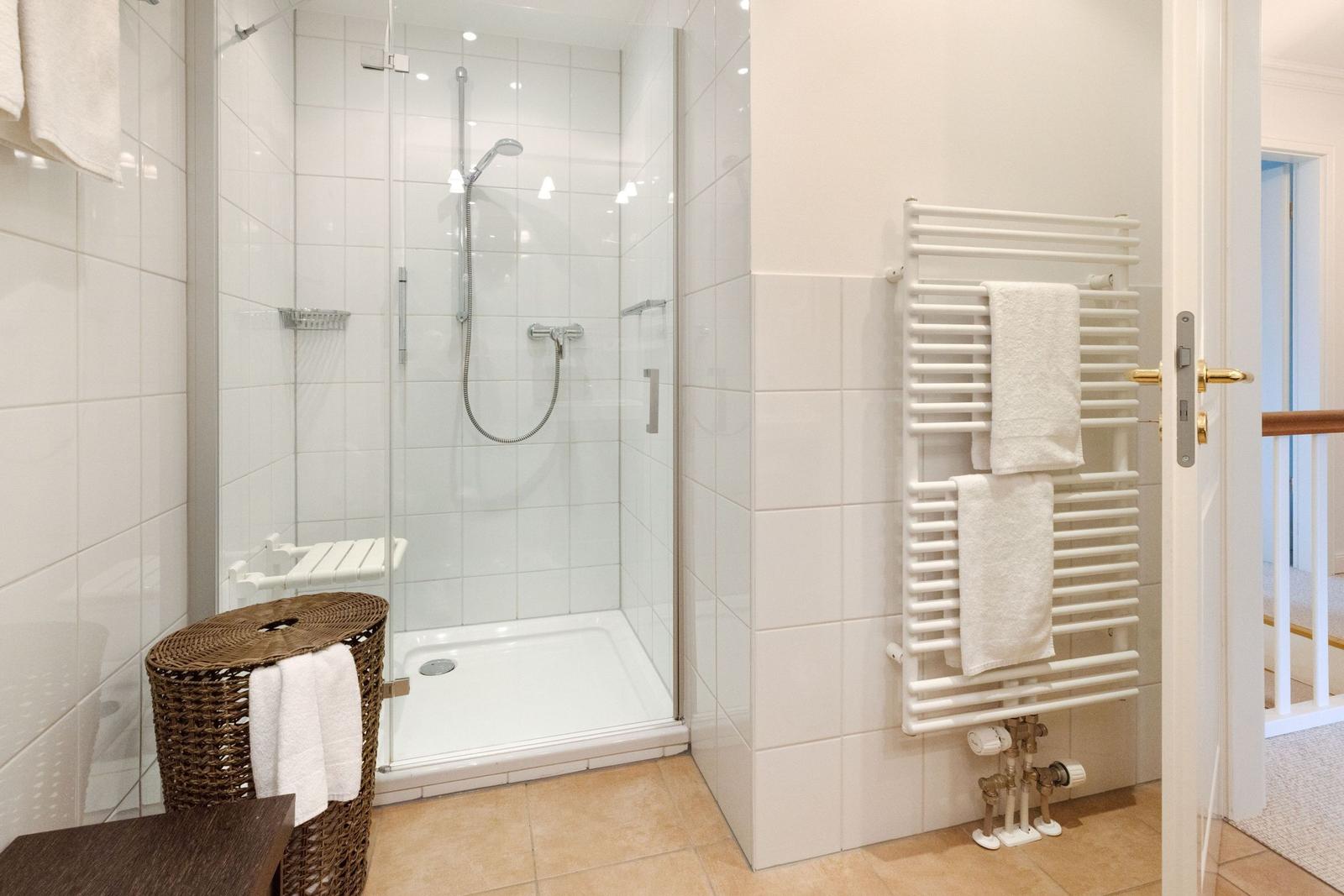 Dusche mit Glaswand, Handtuchhalter und Heizkörper an der Wand.