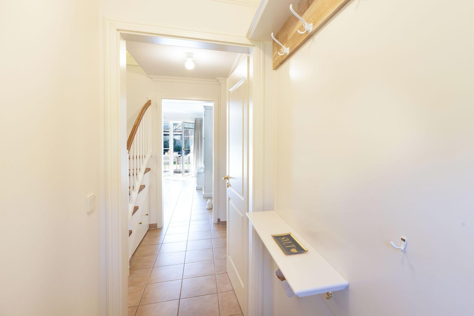 Flur mit Garderobe, Treppenhaus und Blick in Wohnbereich.