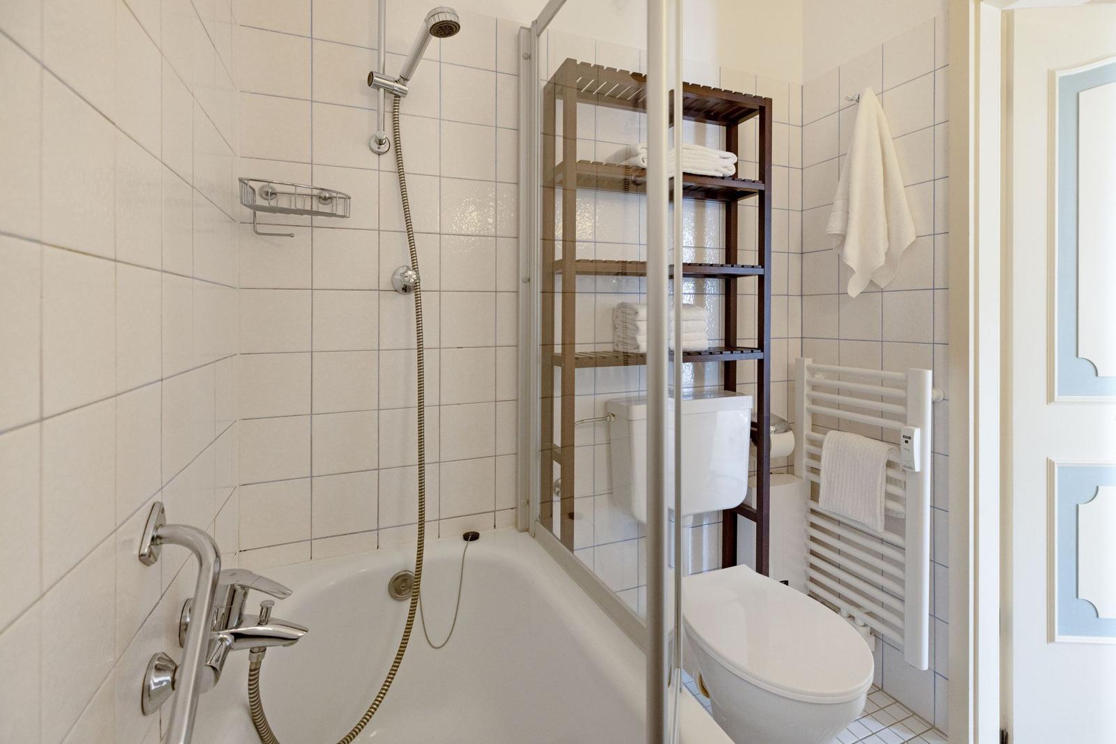 Bad mit Badewanne, Dusche, Toilette und Handtuchhalter.