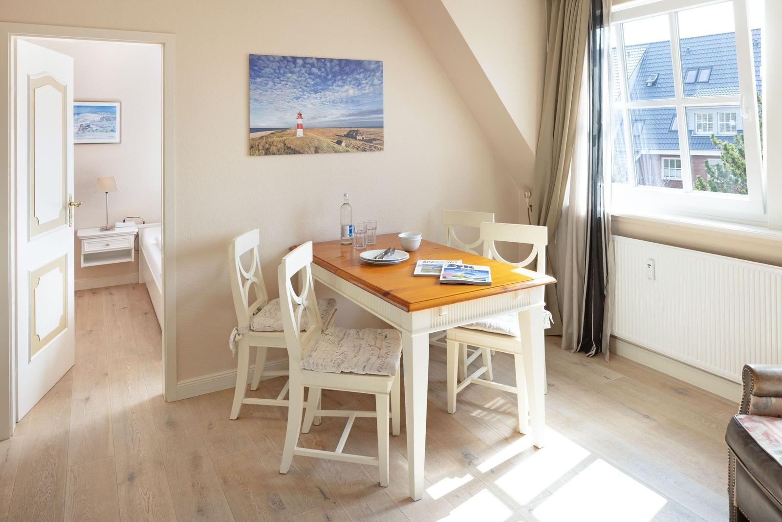 Essbereich mit Tisch und Stühlen. Durchgang zur Schlafzimmer. Wandbild mit Leuchtturm.