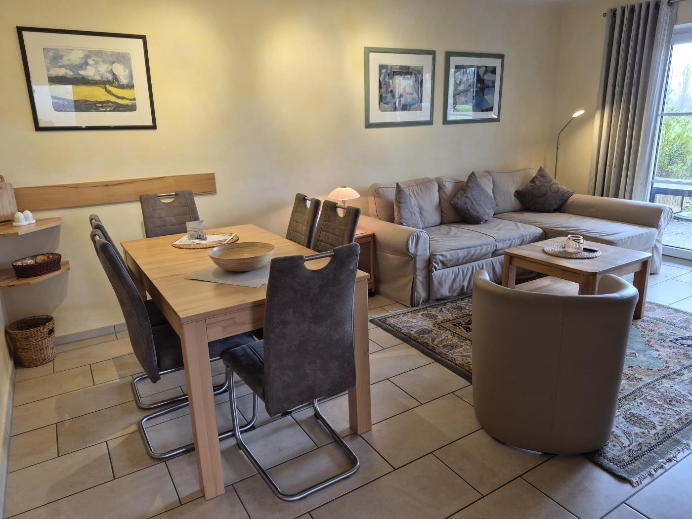 Wohn- und Essbereich mit Sofa, Esstisch und Stühlen sowie Wandbildern.