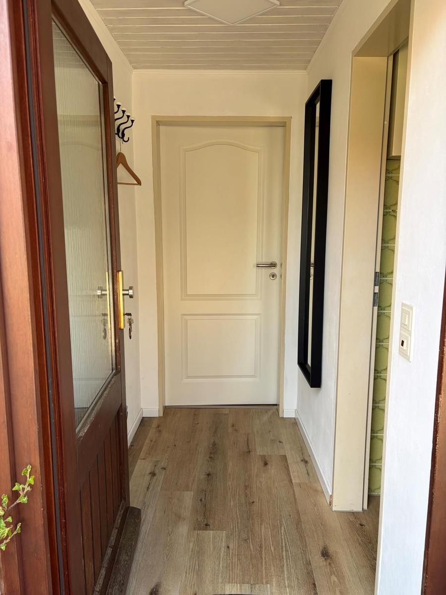 Flur mit Holzboden, weißer Tür und Spiegel an der Wand