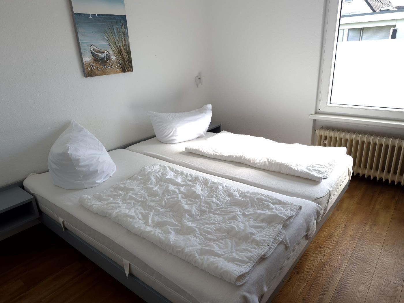 Zwei Einzelbetten mit weißen Bettwäschen und einem Wandbild.