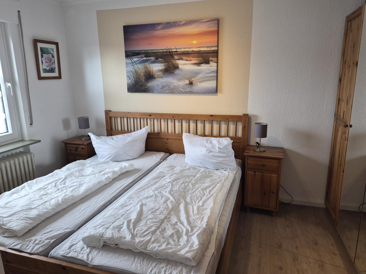 Schlafzimmer mit Doppelbett, zwei Nachttischen und Wandbild.