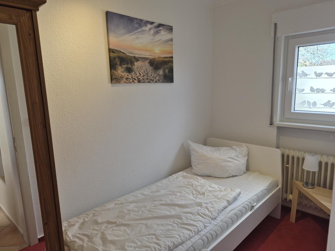 Ein Schlafzimmer mit einem Bett, einem Fenster und einer Wanddekoration.