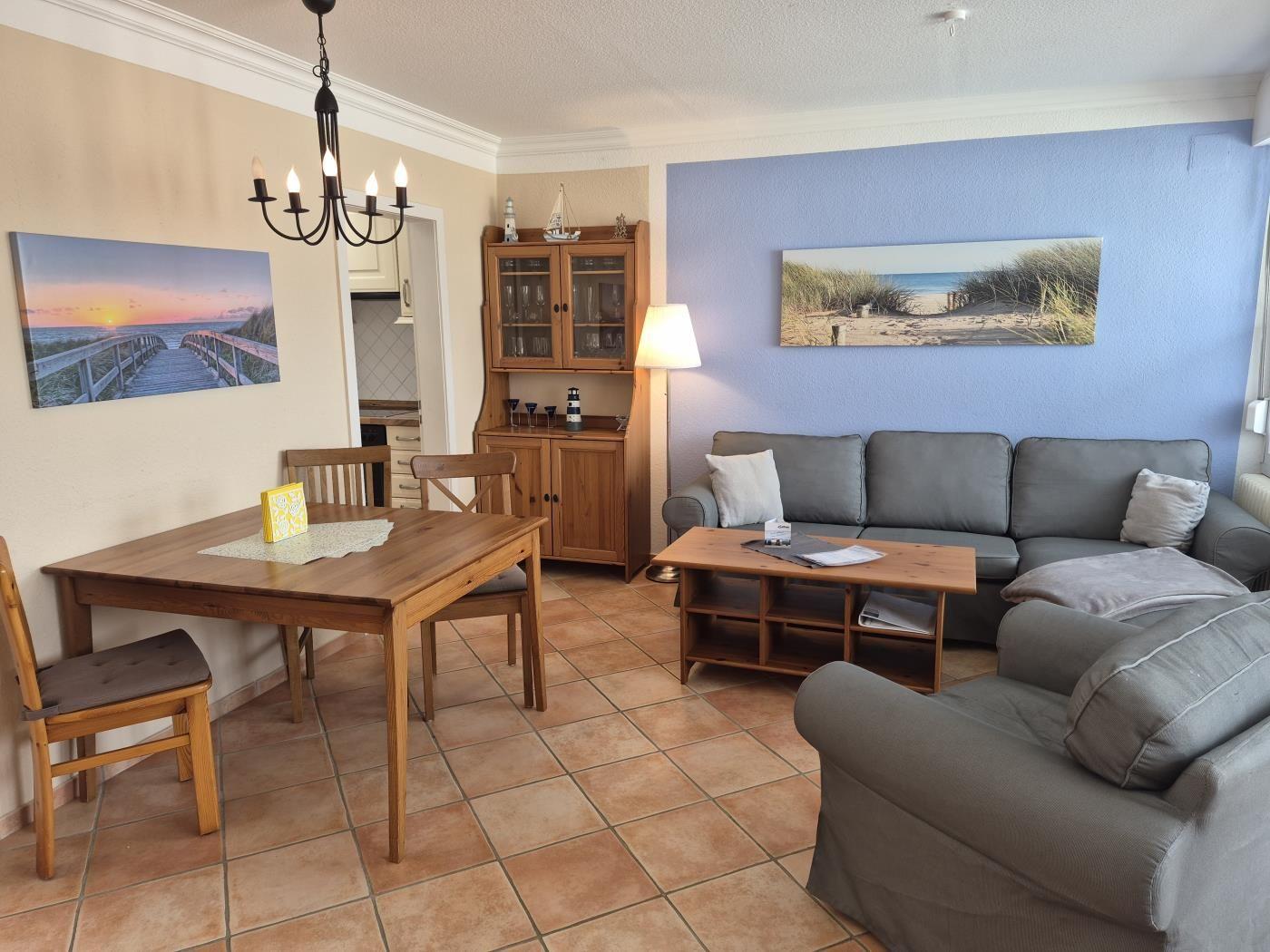 Wohn- und Essbereich mit Sofa, Tisch, Stühlen und Küchenansicht.