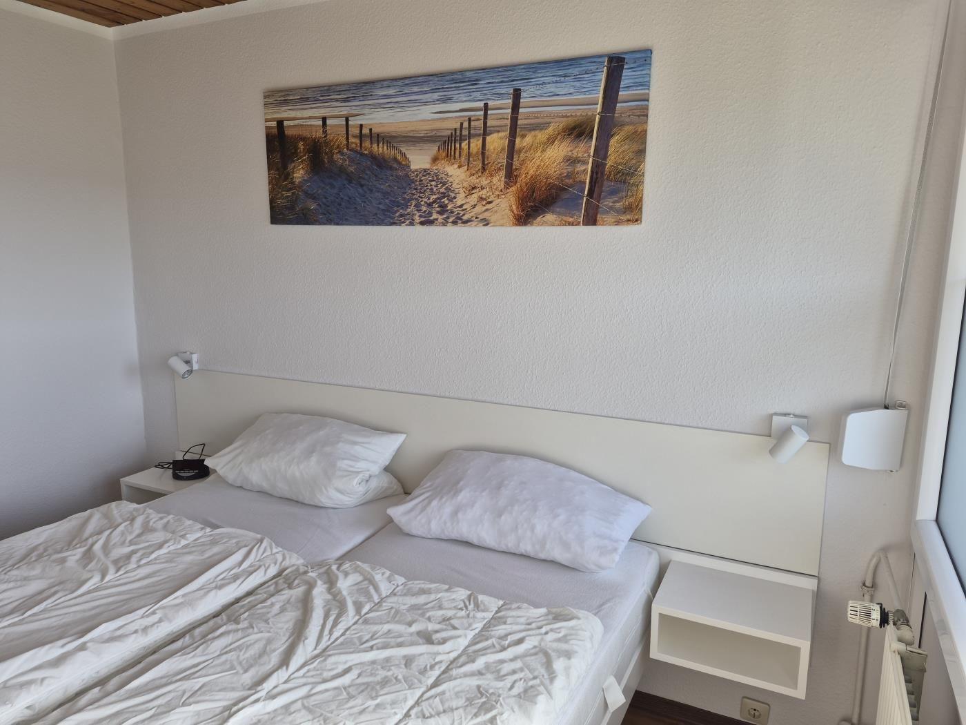 Schlafzimmer mit Bett, Wandbild und Nachttischen