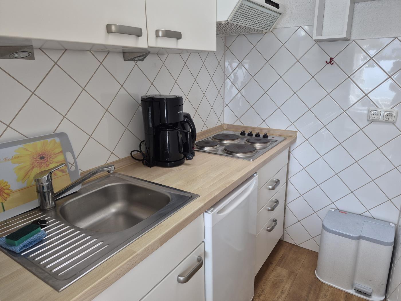 Küche mit Spüle, Kochfeld und Kaffeemaschine