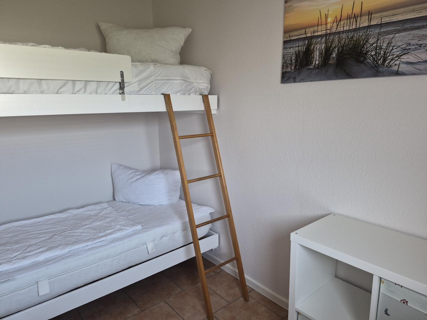 Zimmer mit Doppelstockbett, Holzleiter und Wandbild an der Wand.