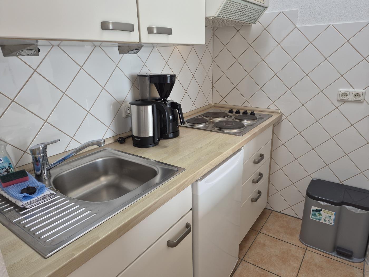 Küche mit Spüle, Herd, Kaffeemaschine und Kühlschrank.
