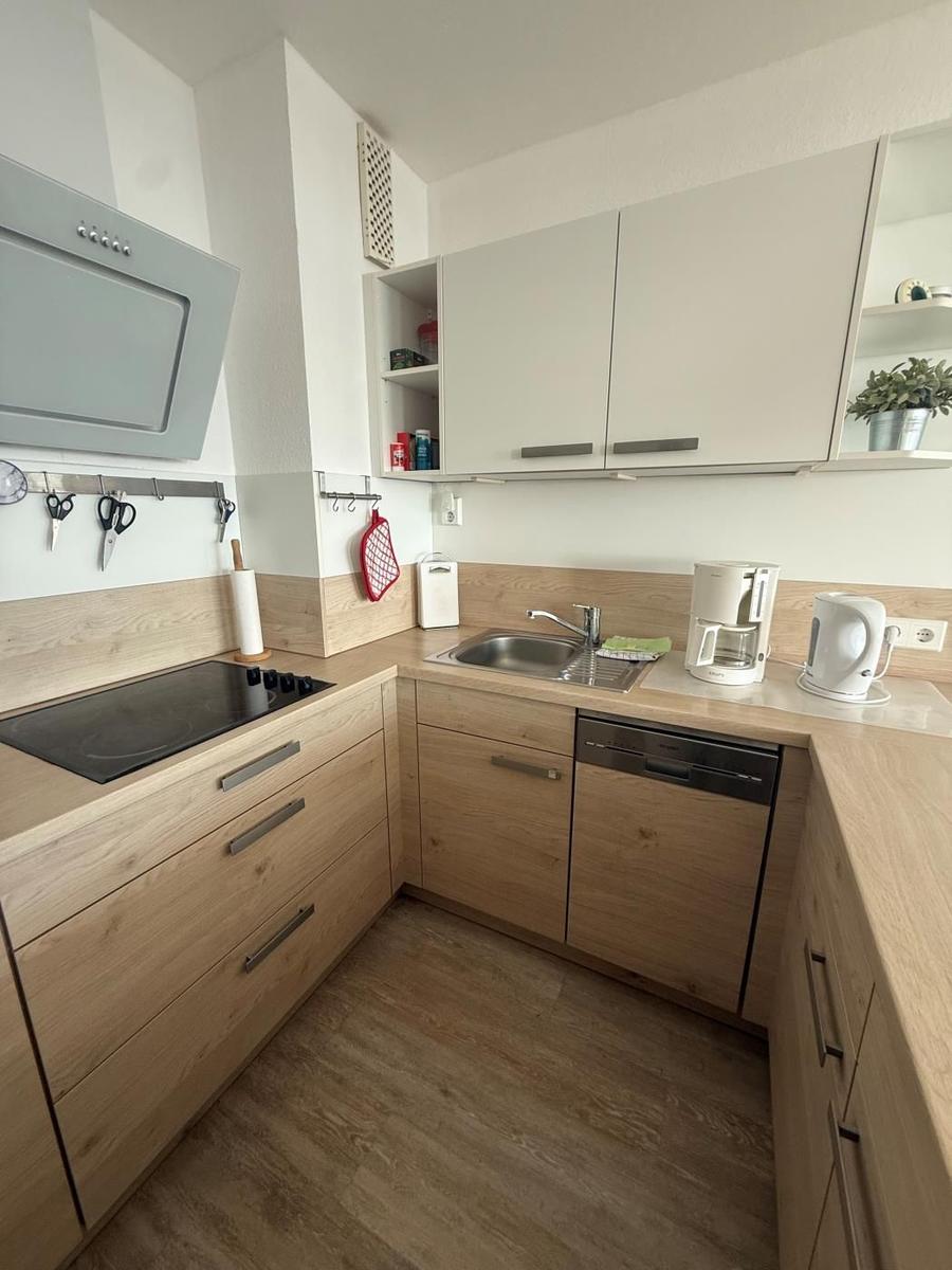 Küche mit Holzfronten, Spüle, Kaffeemaschine und Kühlschrank.