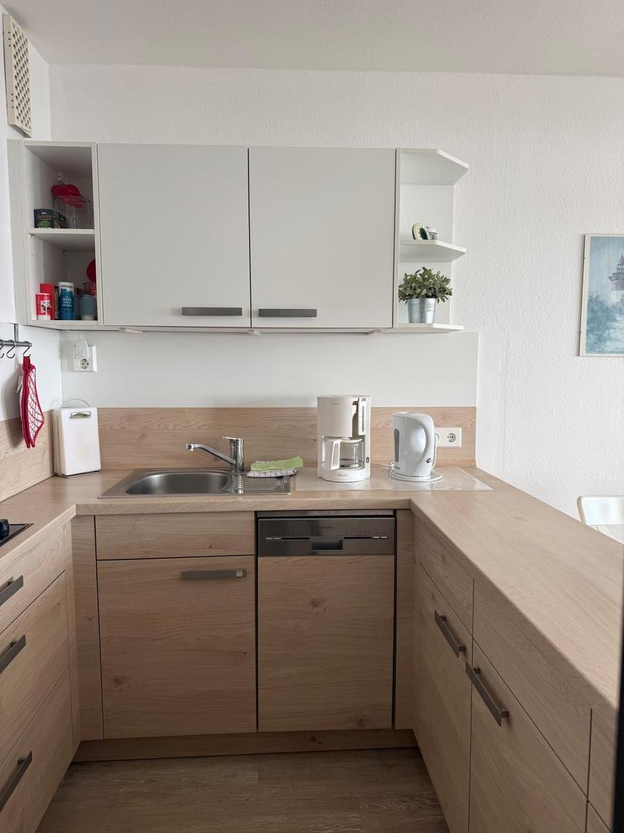 Küche mit Holzfronten, Spüle, Kaffeemaschine und Kühlschrank.