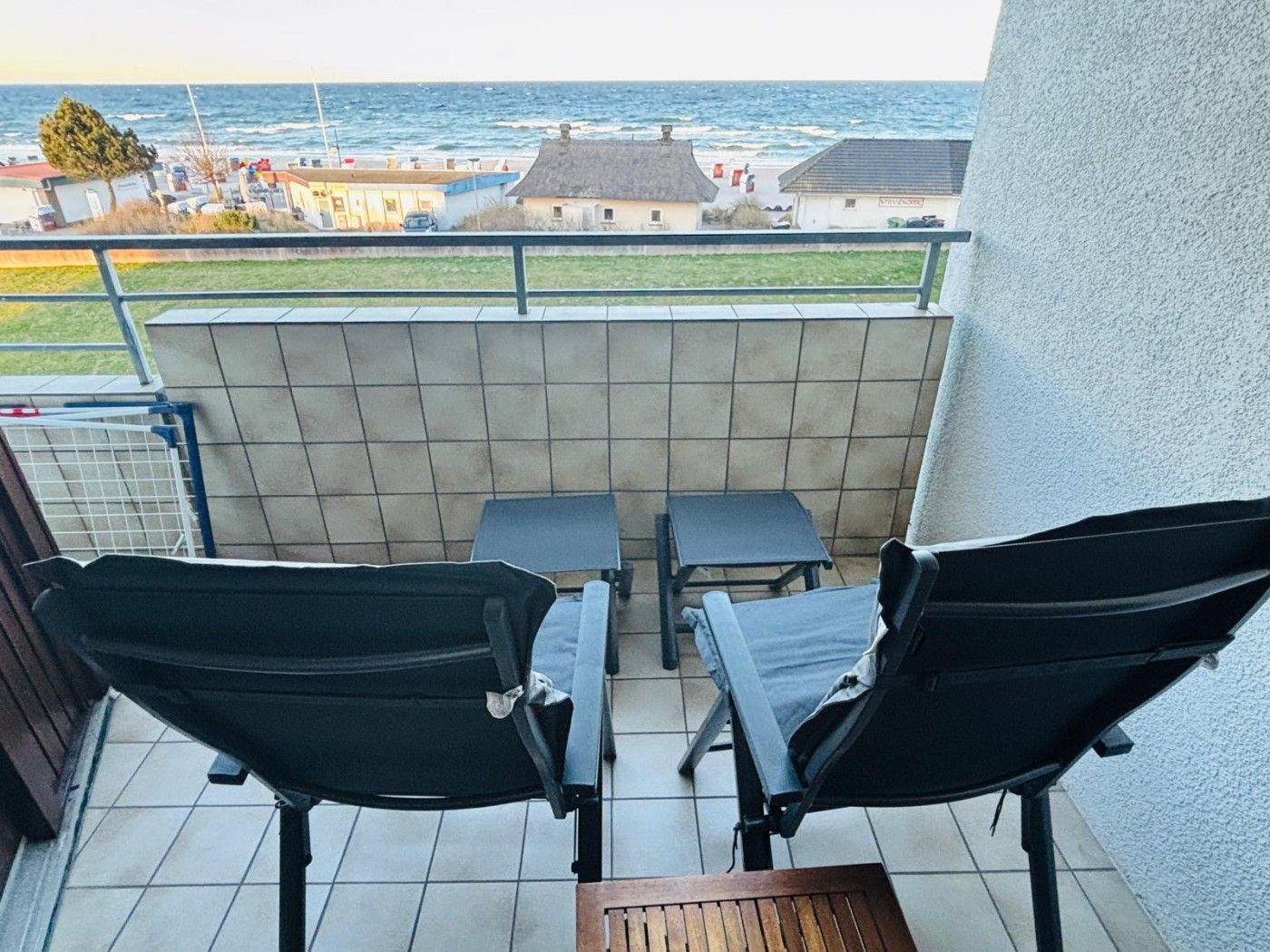 Balkon mit zwei Stühlen und Tisch, Blick auf Meer und Strand.