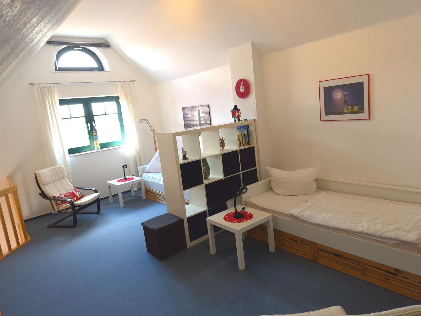 Schlafzimmer mit zwei Betten, Bücherregal und Fenster mit Blick.