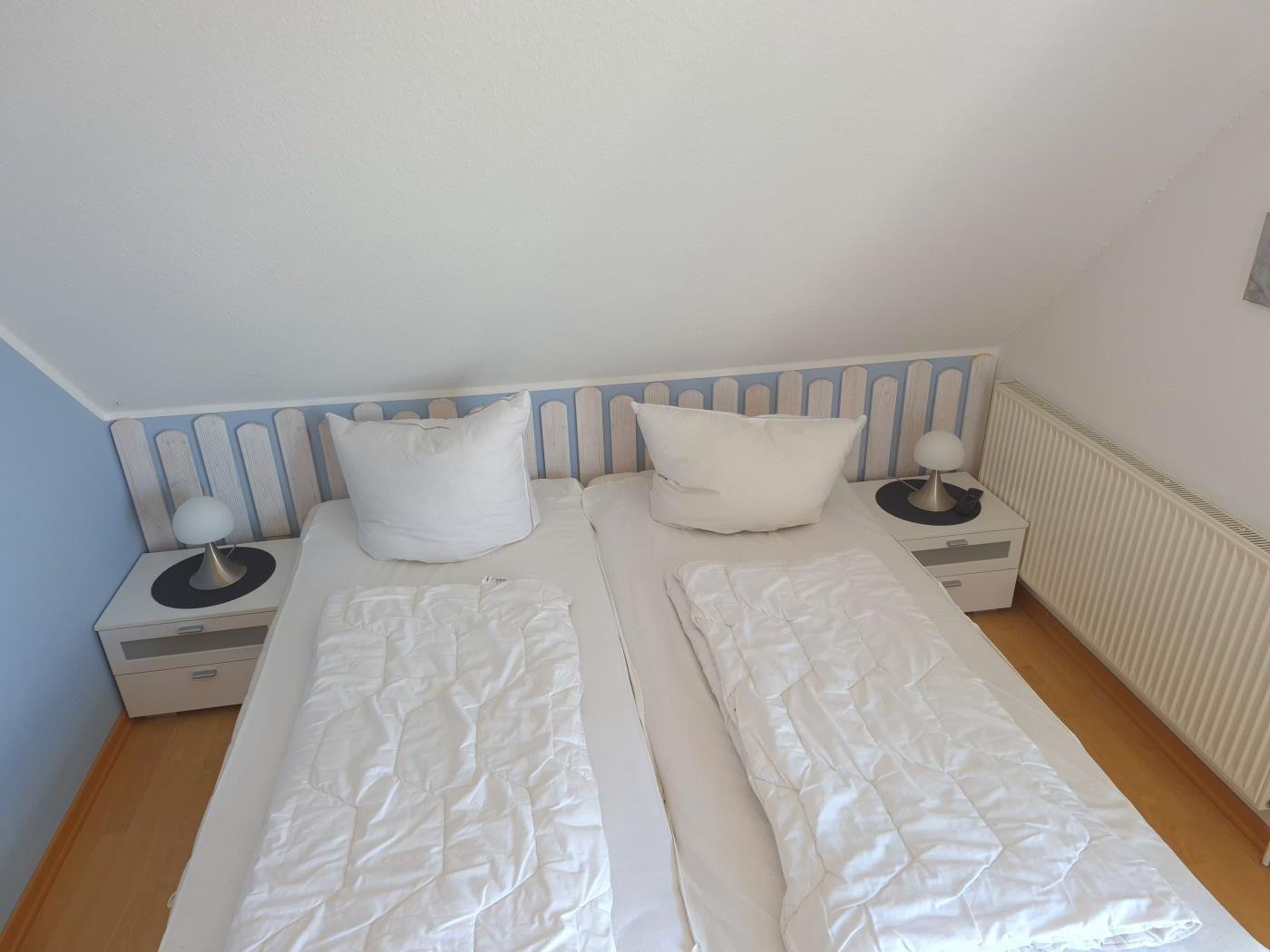 Zimmer mit Doppelbett, zwei Nachttischen und Heizkörper an der Wand.