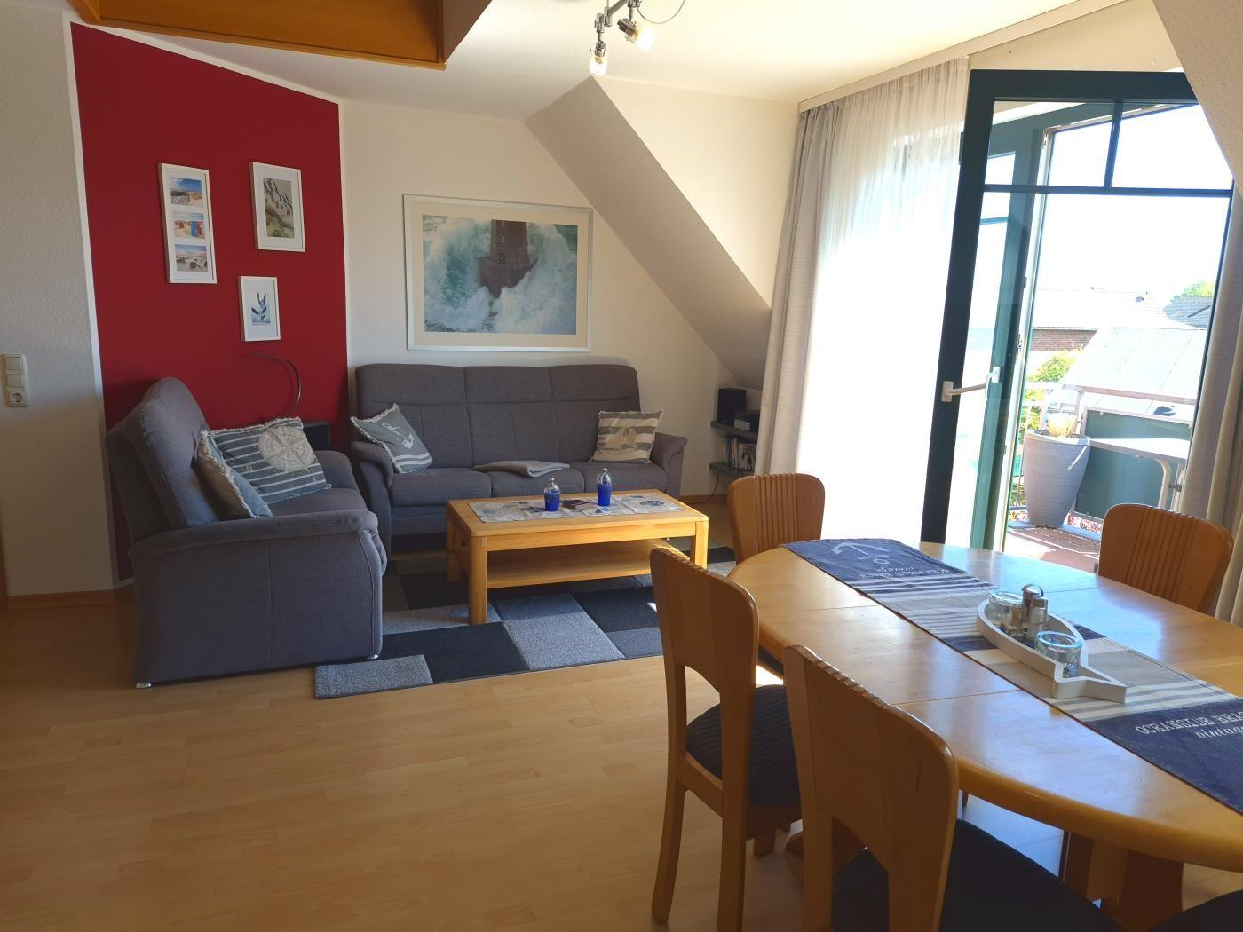 Wohn- und Essbereich mit Sofa, Tisch und Sitzgelegenheiten. Durchgang zur Terrasse.