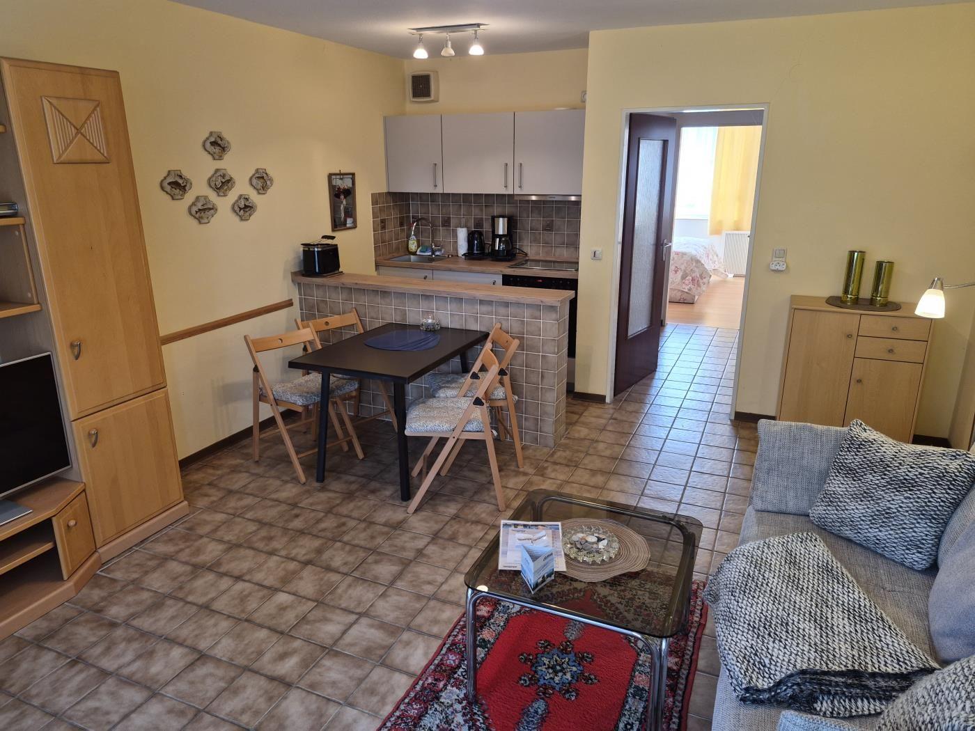 Wohnung mit Essbereich, Küche und Schlafzimmer. Holzmöbel, Sofa und Teppich.