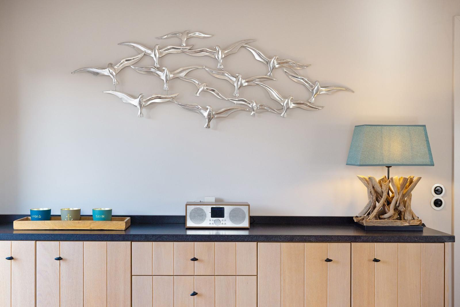 Wanddekoration mit fliegenden Vögeln, Lampe und Radio auf Küchenzeile.