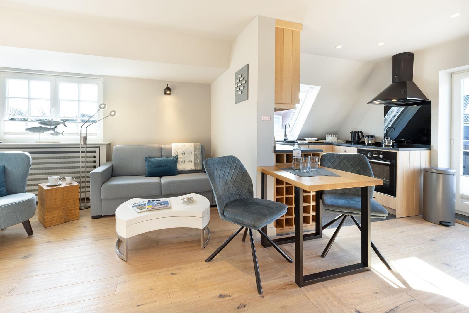 Wohn- und Küchenbereich mit Sofa, Tisch und moderner Einrichtung.
