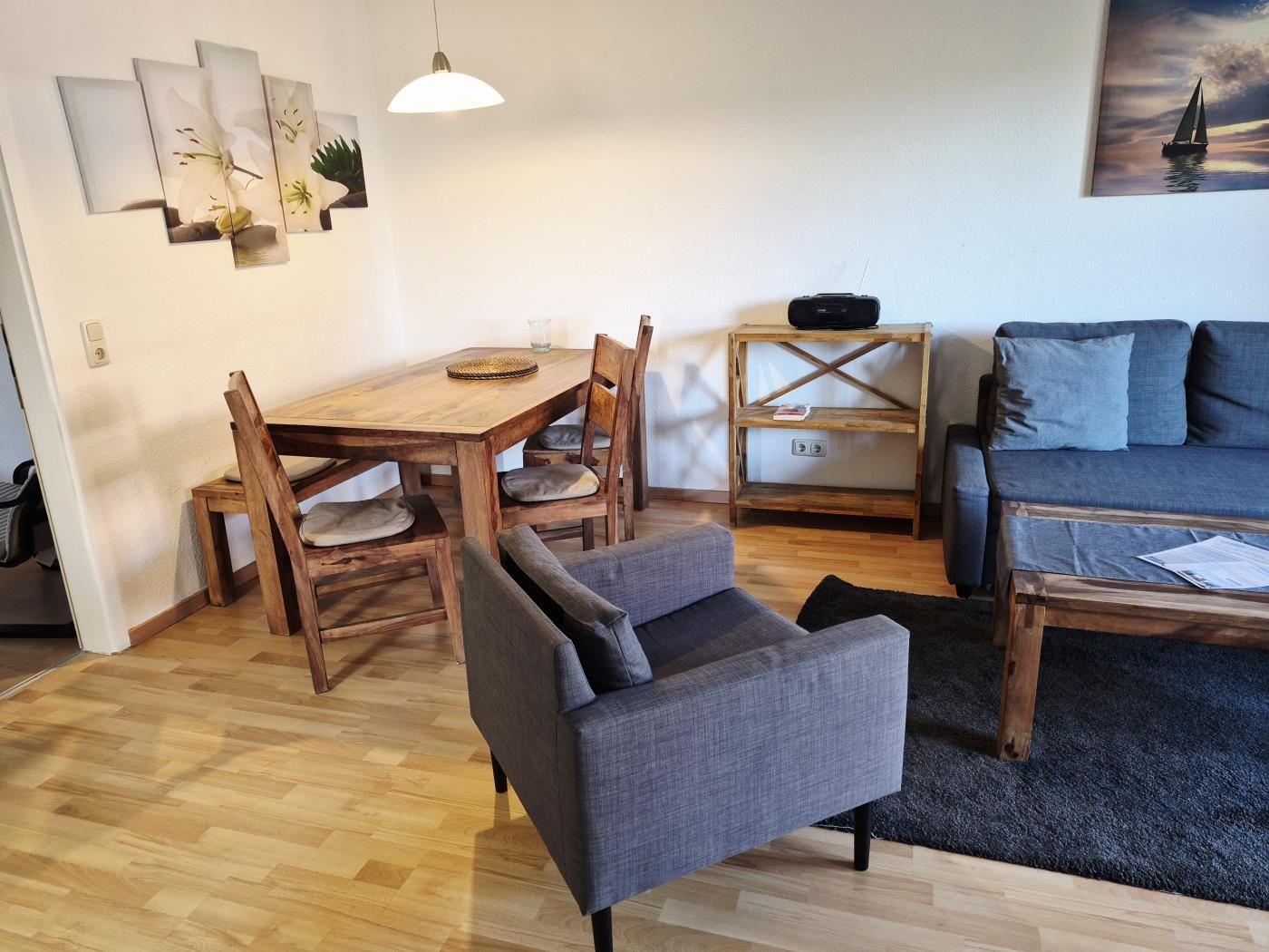 Wohn- und Essbereich mit Holztisch, Stühlen, Sofa und Sessel.