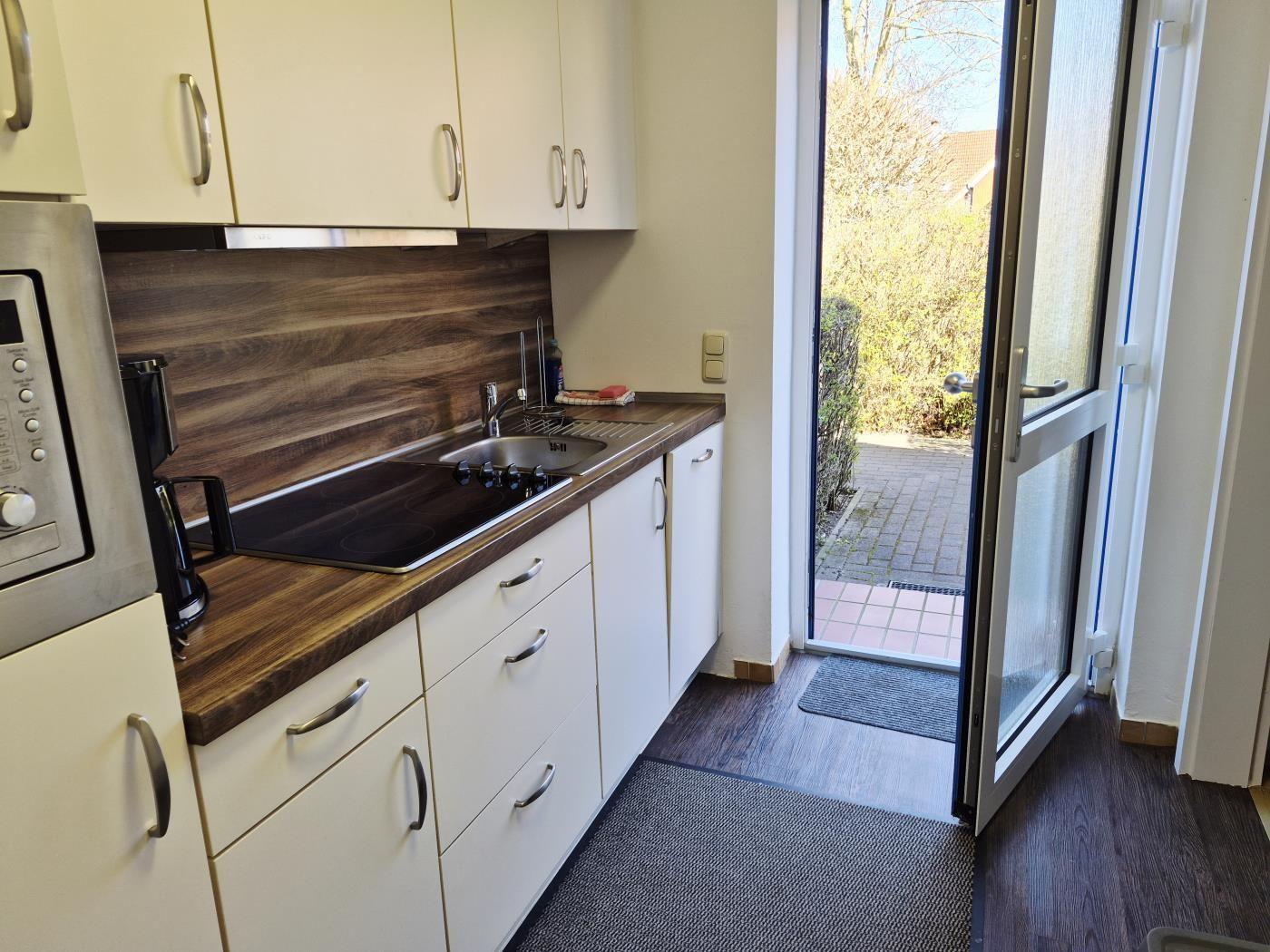 Küche mit Arbeitsfläche, Spüle und Fenster zur Terrasse