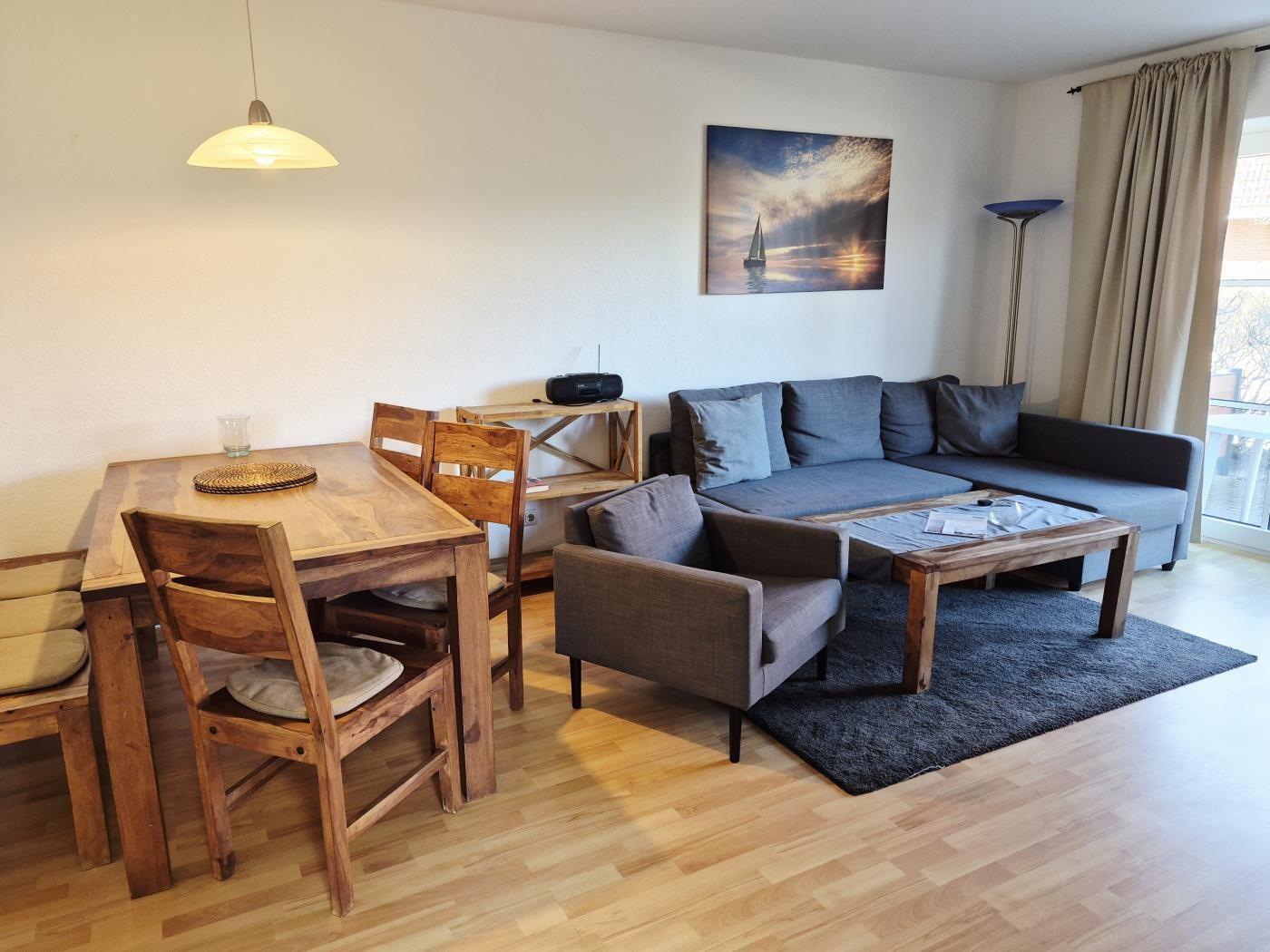 Wohn- und Essbereich mit Holztisch, Sofa und Bild an der Wand.