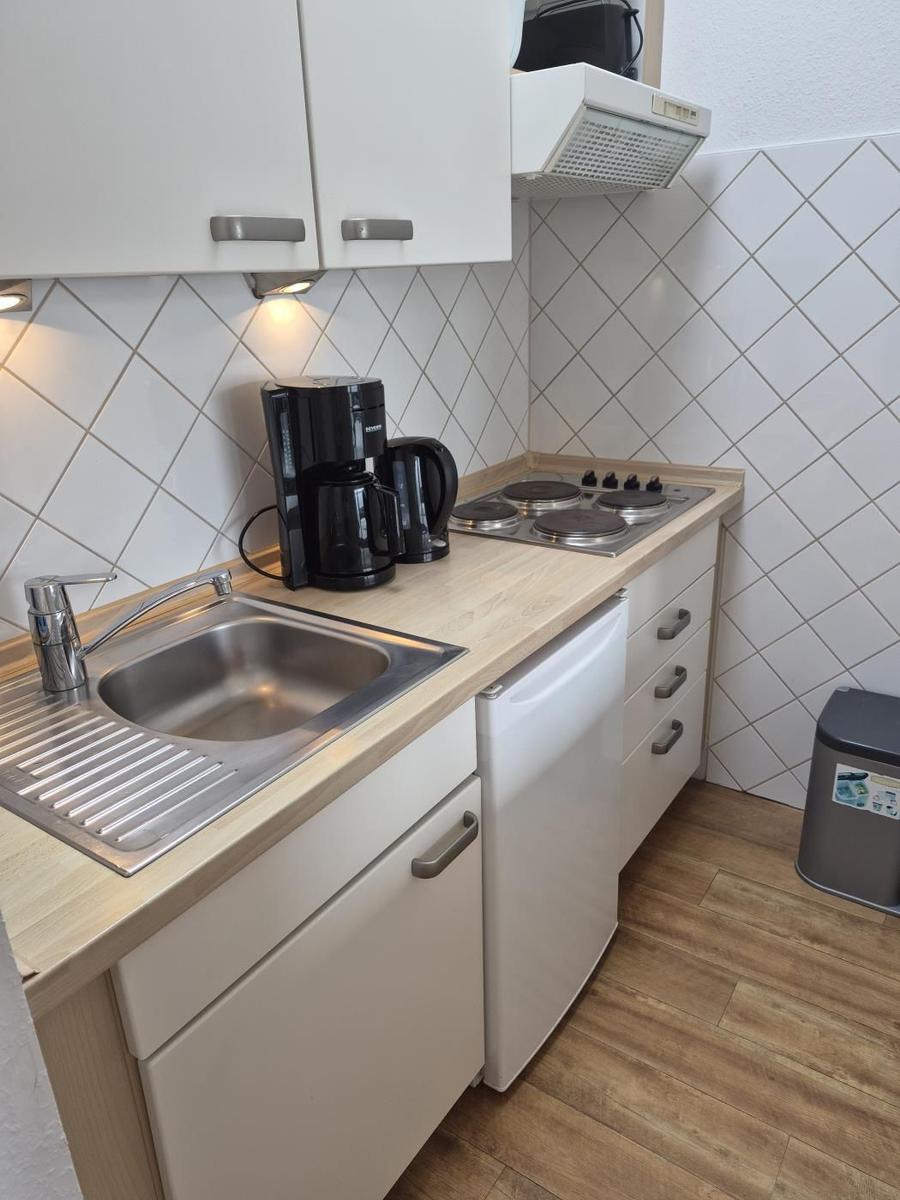 Küche mit Spüle, Herd, Kaffeemaschine und Kühlgerät.