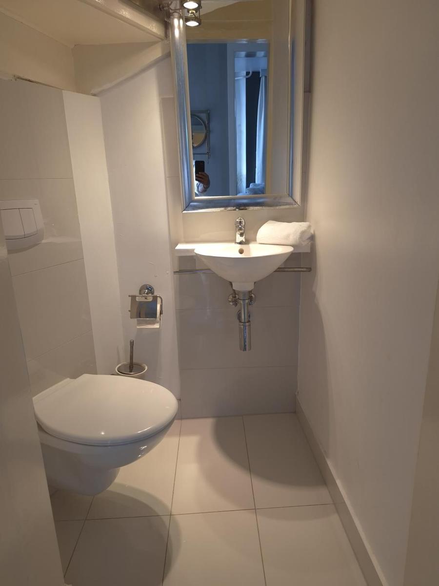 Badezimmer mit Toilette, Waschbecken und Spiegel.
