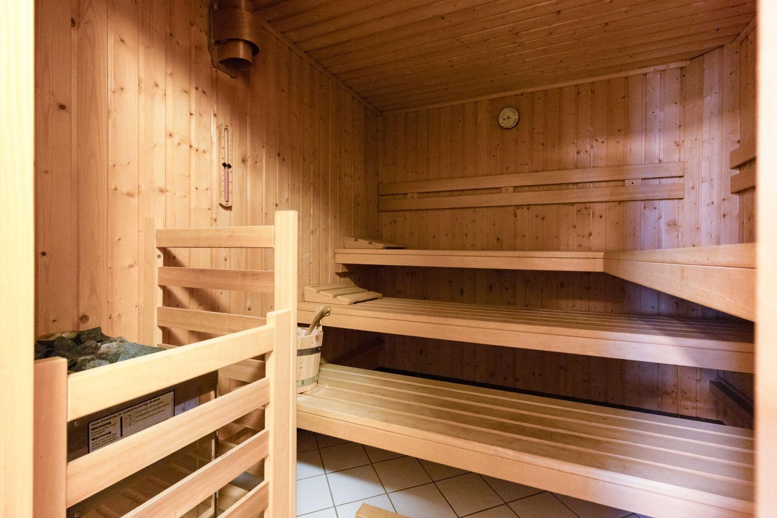 Sauna mit Holzbanken und Thermometer an der Wand.