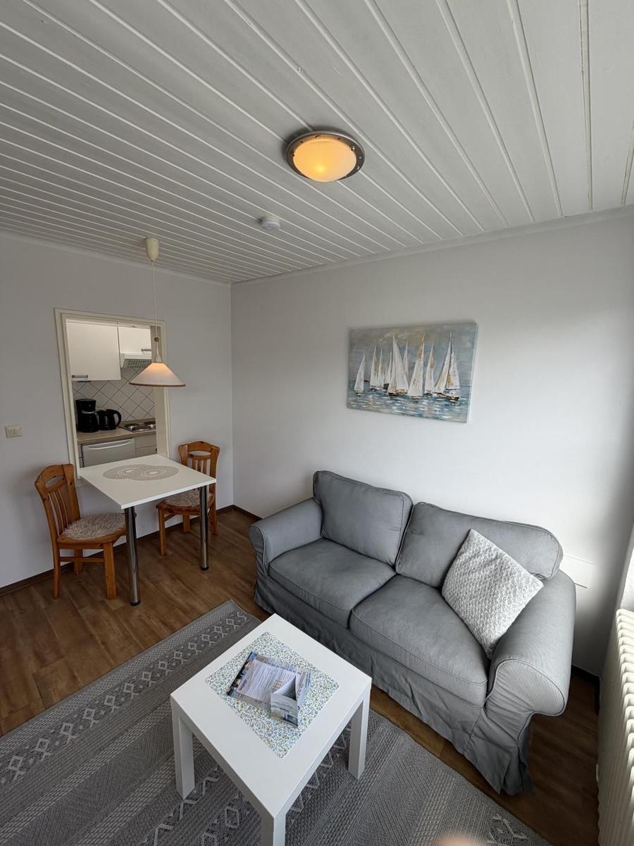 Wohnzimmer mit Sofa, Tisch und Bild an der Wand. Küche im Hintergrund.