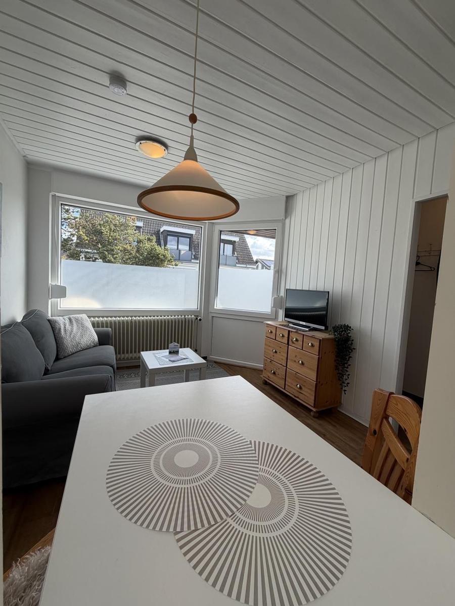 Wohnzimmer mit Sofa, TV und Esstisch mit Platzdecken.
