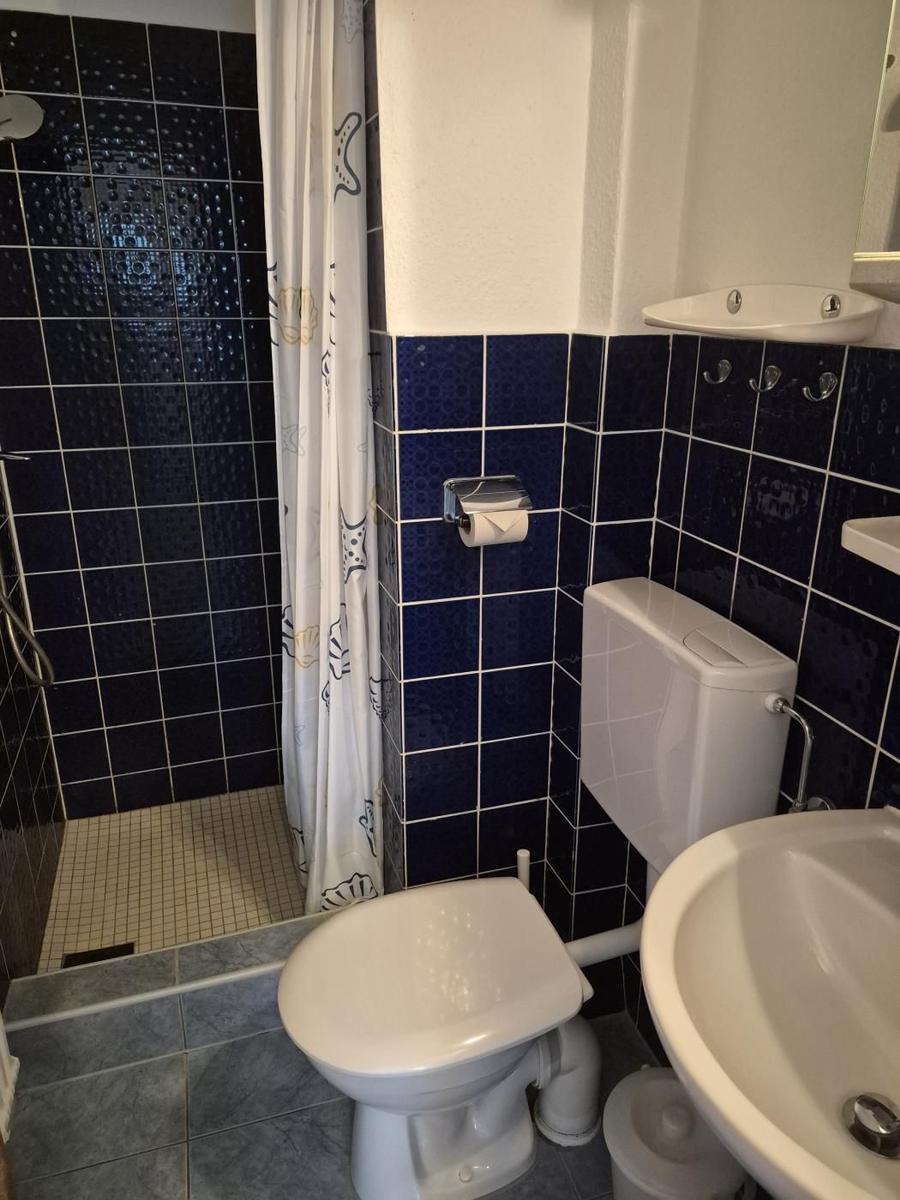 Badezimmer mit Dusche, WC und Waschbecken. Wände mit blauen Fliesen.