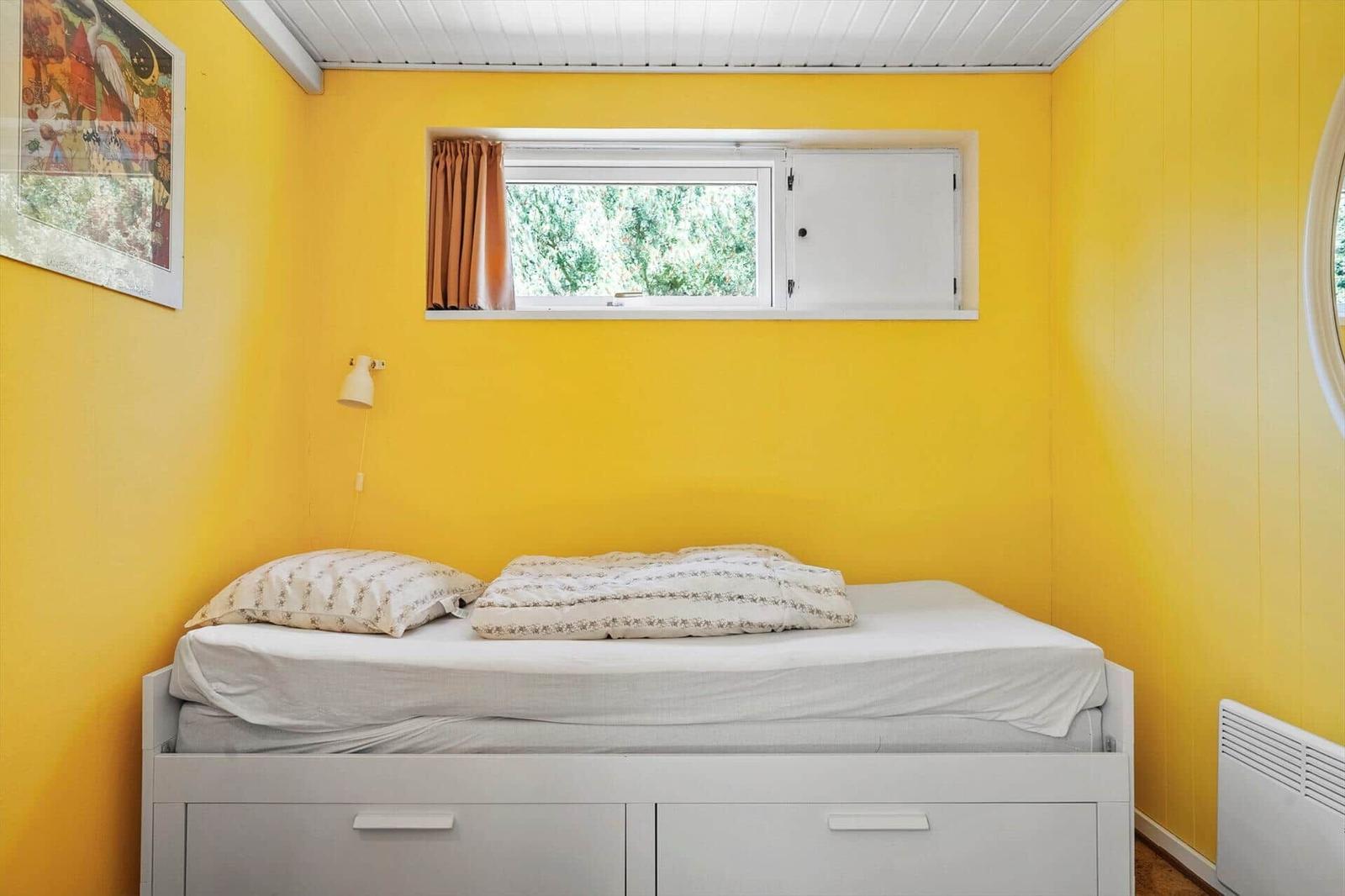 Ein Schlafzimmer mit gelben Wänden, einem Bett und einem Fenster.