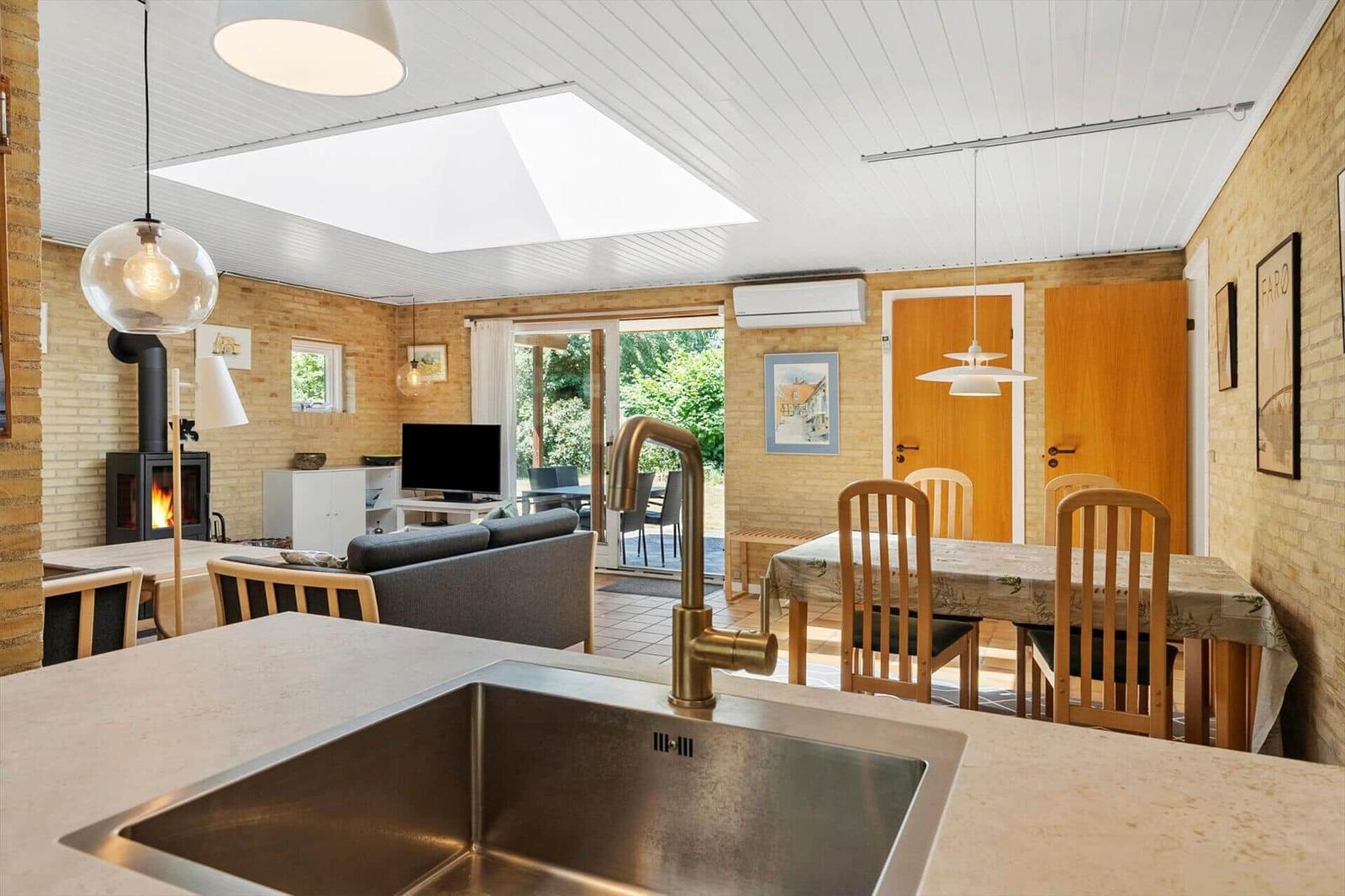 Küche mit Essbereich, Wohnzimmer und Kamin. Draußen ist eine Terrasse mit Blick auf Grün.