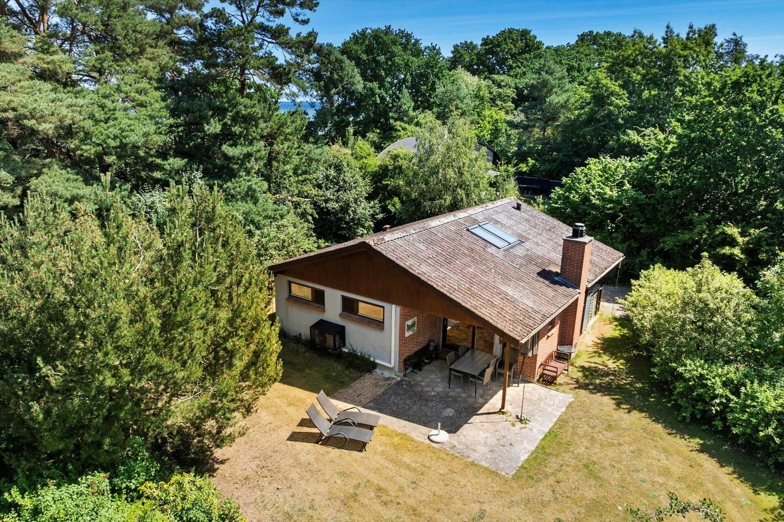 Haus mit Terrasse, Garten und Blick auf den Wald und Meer.