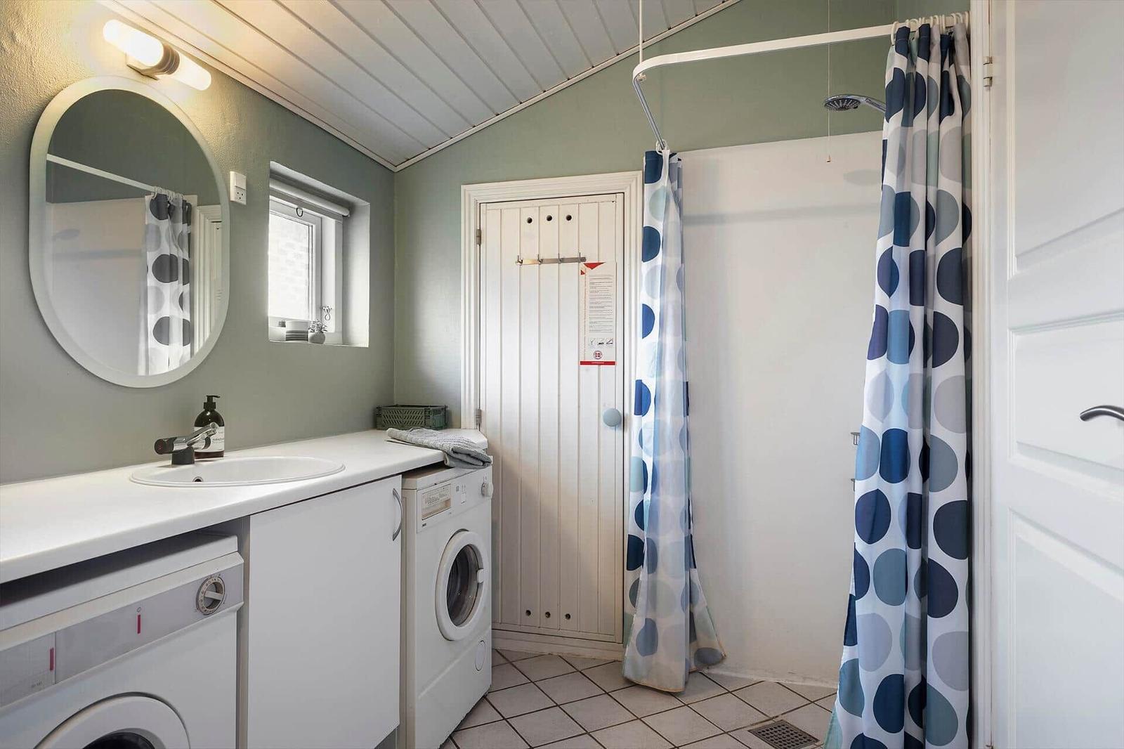 Badezimmer mit Dusche, Waschmaschine und Spiegel