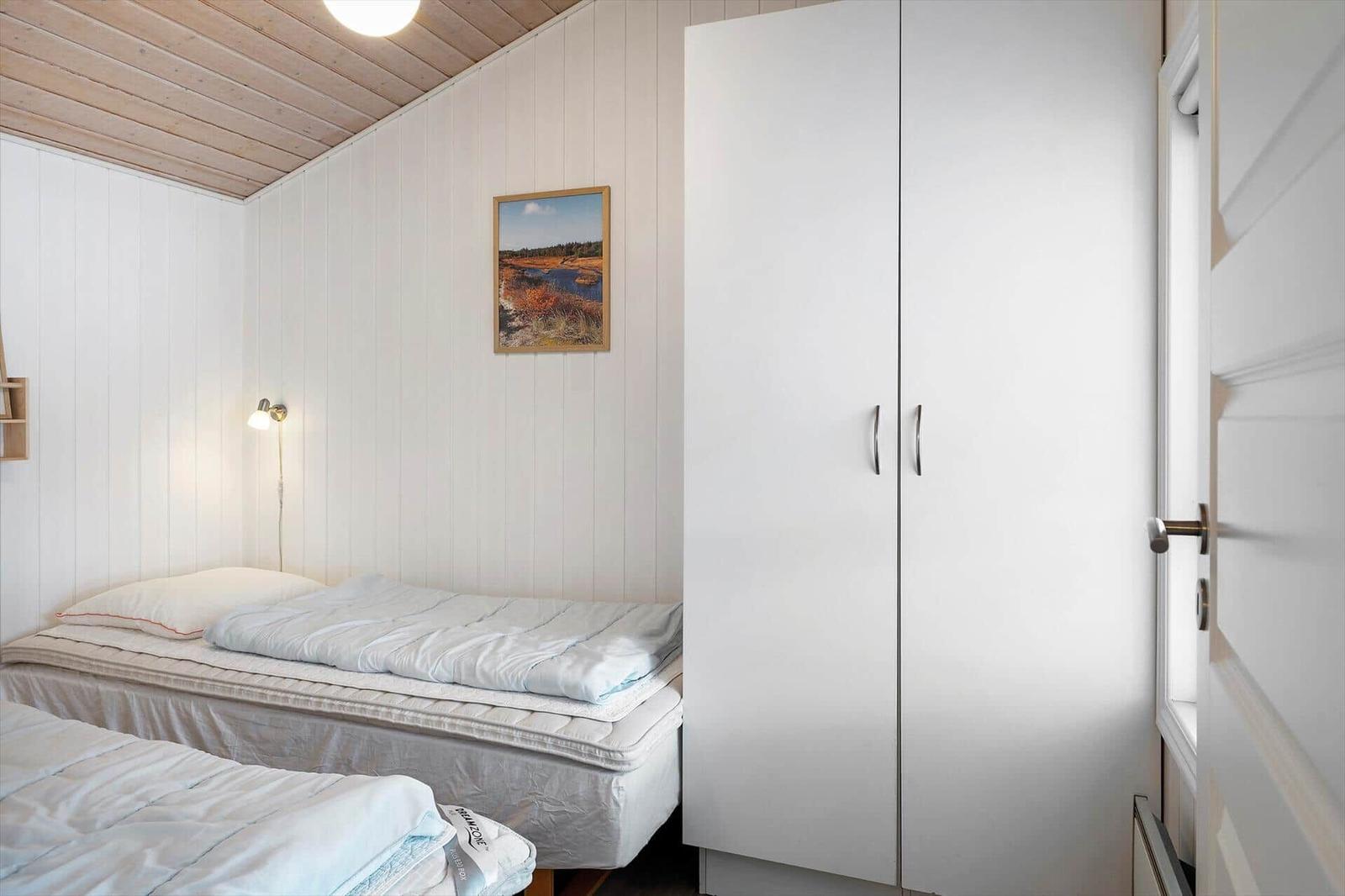 Zimmer mit zwei Betten, weißem Schrank und Wandbild