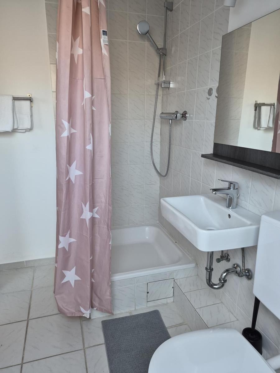 Bathroom with shower, sink, and toilet. Shower curtain with star pattern.