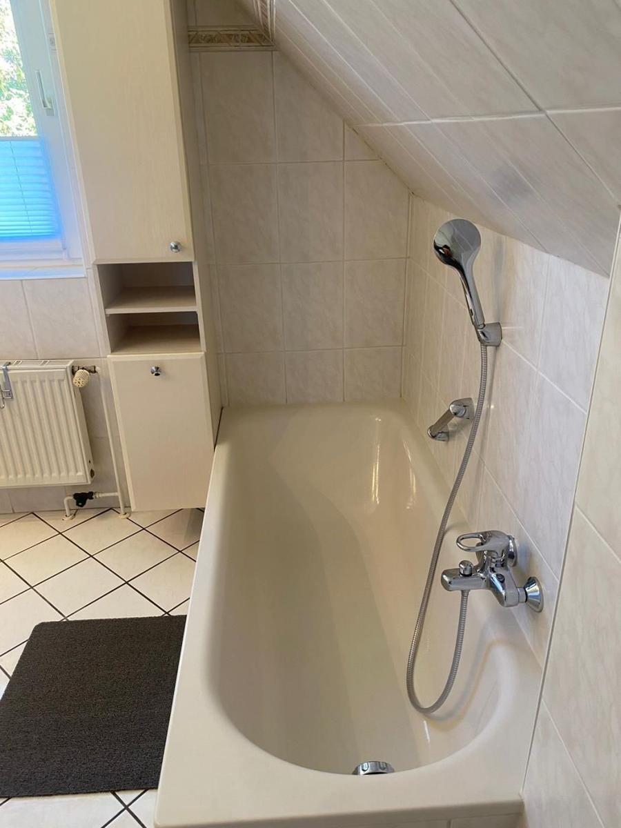 Bad mit Badewanne, Duschbrause und Schränken unter Dachschrägen.