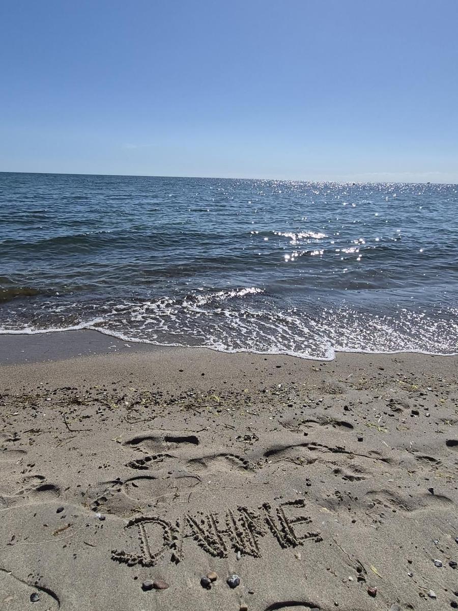 Sandstrand mit Wellen, wo DANKE in den Sand geschrieben steht.