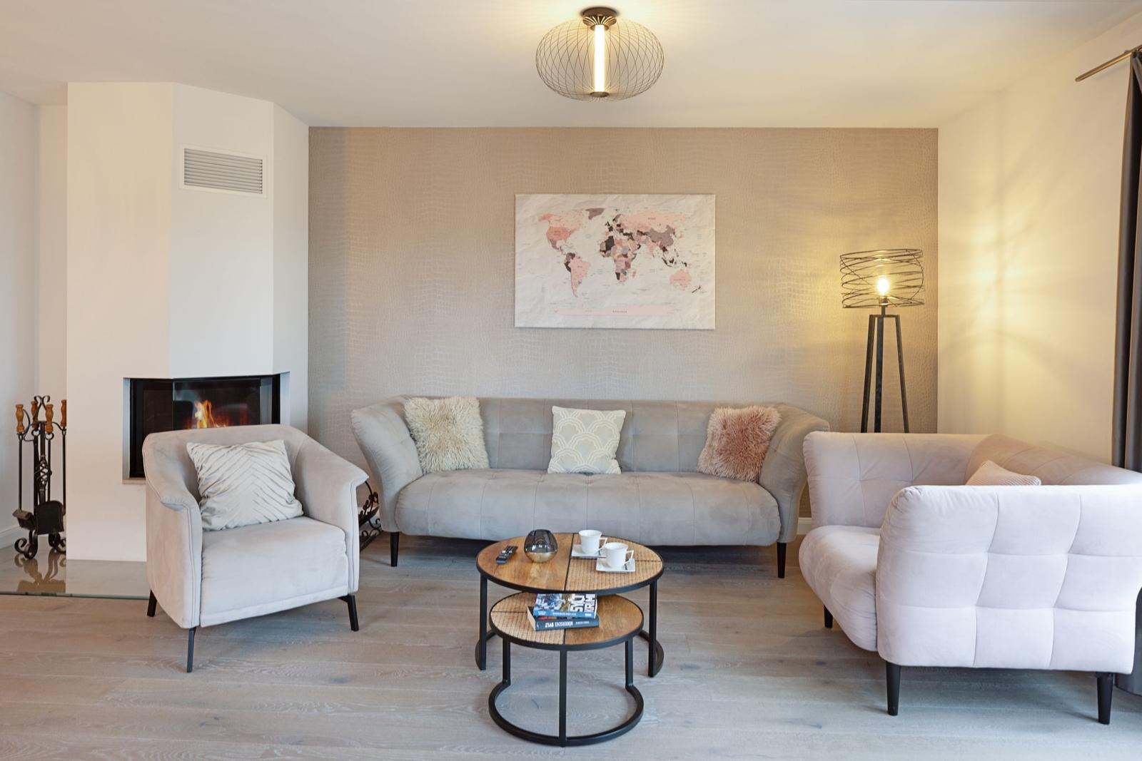 Wohnzimmer mit Sofa, Sesseln, Kamin und Weltkarte an der Wand.