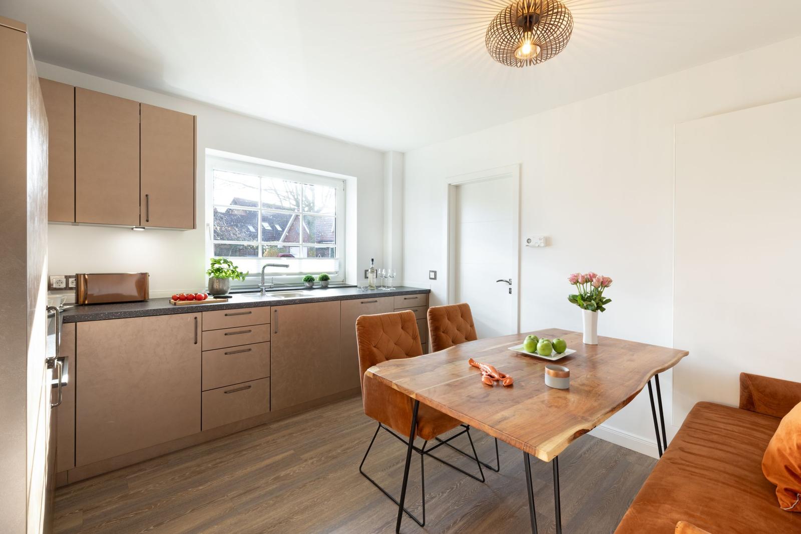 Küche mit Essbereich, Holztisch, braune Stühle und Fenster mit Blick.