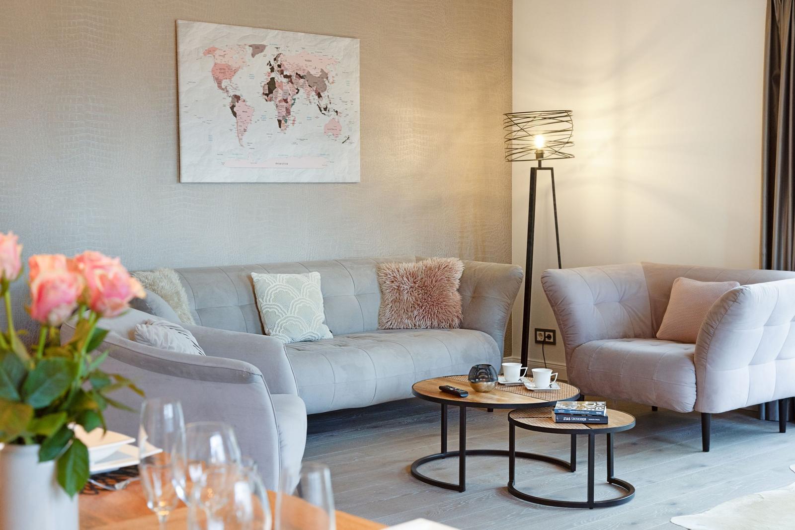 Wohnzimmer mit Sofa, Sessel, Couchtisch und Weltkarte an der Wand.