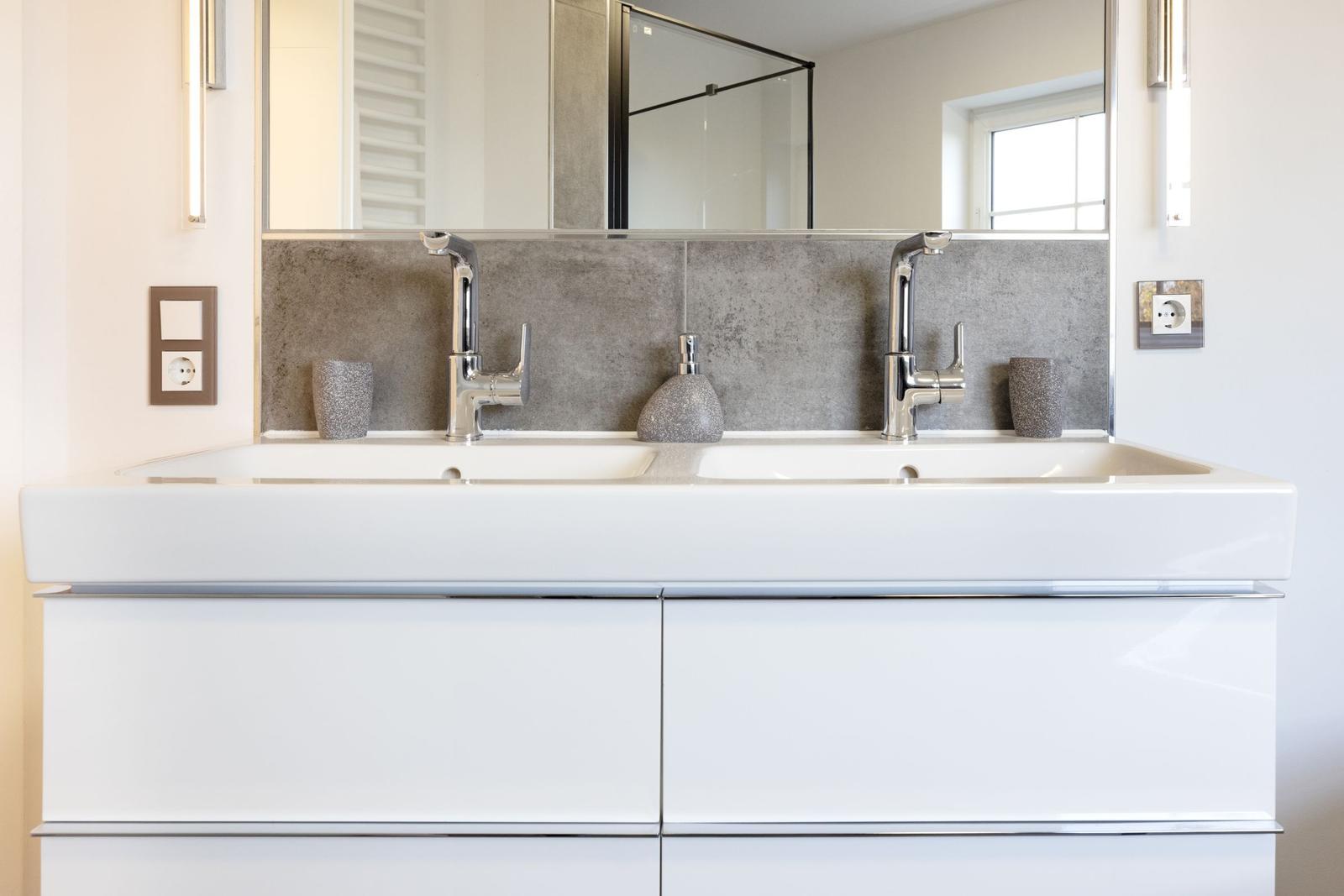 Doppelwaschbecken mit Spiegel und Glasdusche im Badezimmer.