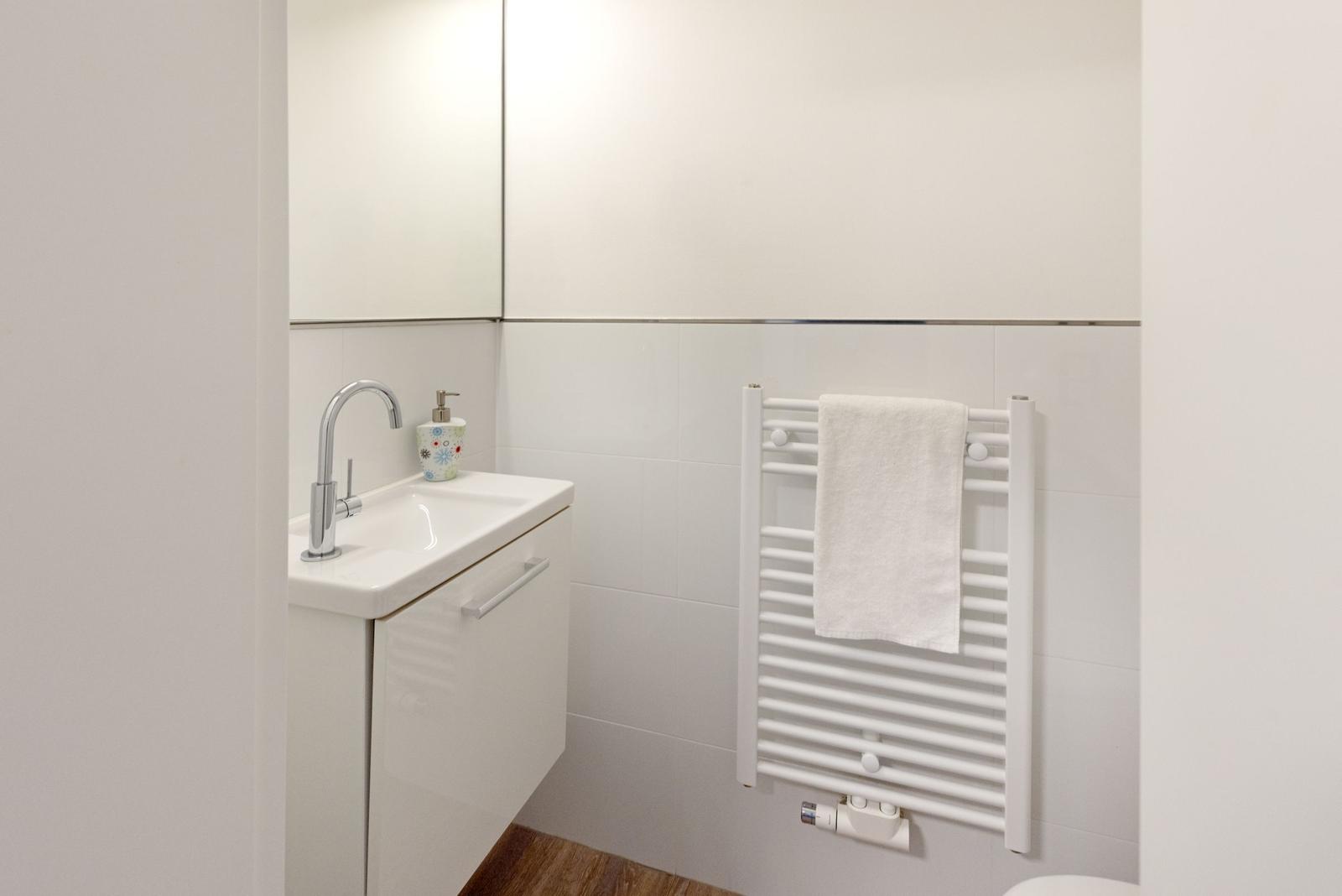 Badezimmer mit Waschbecken, Spiegel und Handtuchhalter.