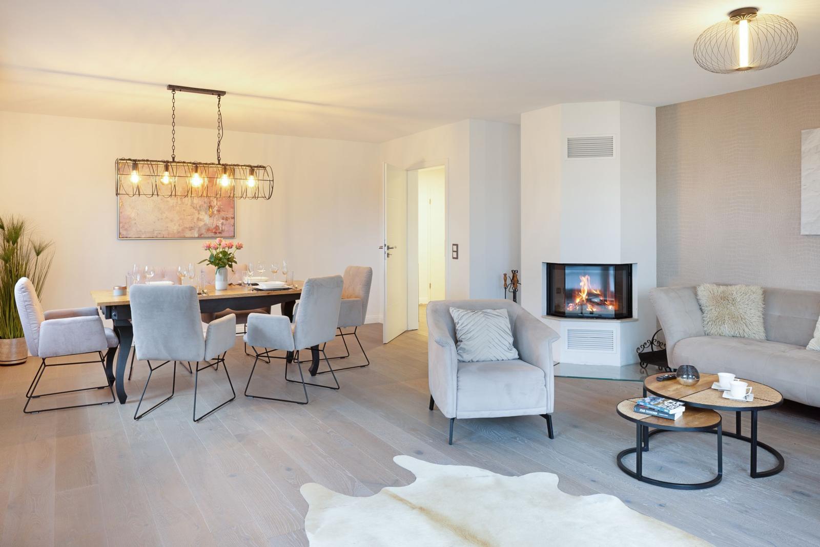 Wohn- und Essbereich mit Kamin, Sitzgelegenheiten und Esstisch mit Stühlen.