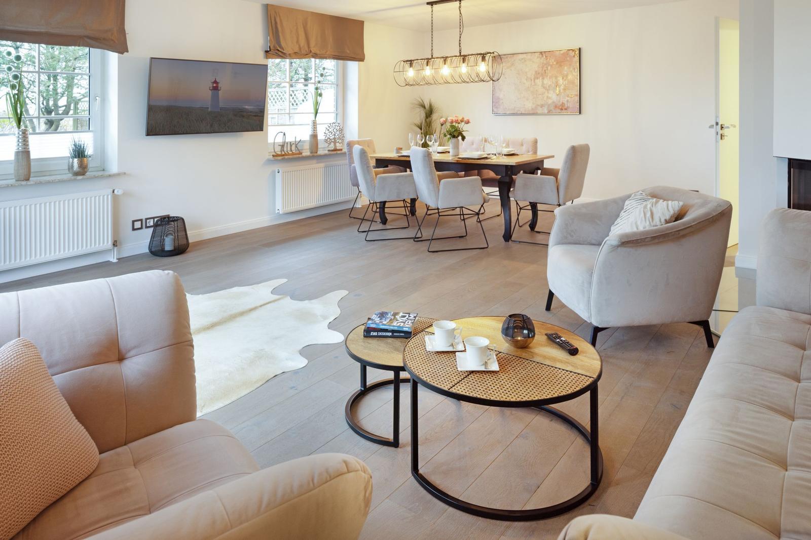 Wohn- und Essbereich mit hellen Möbeln, Holzboden und Fernseher an der Wand.