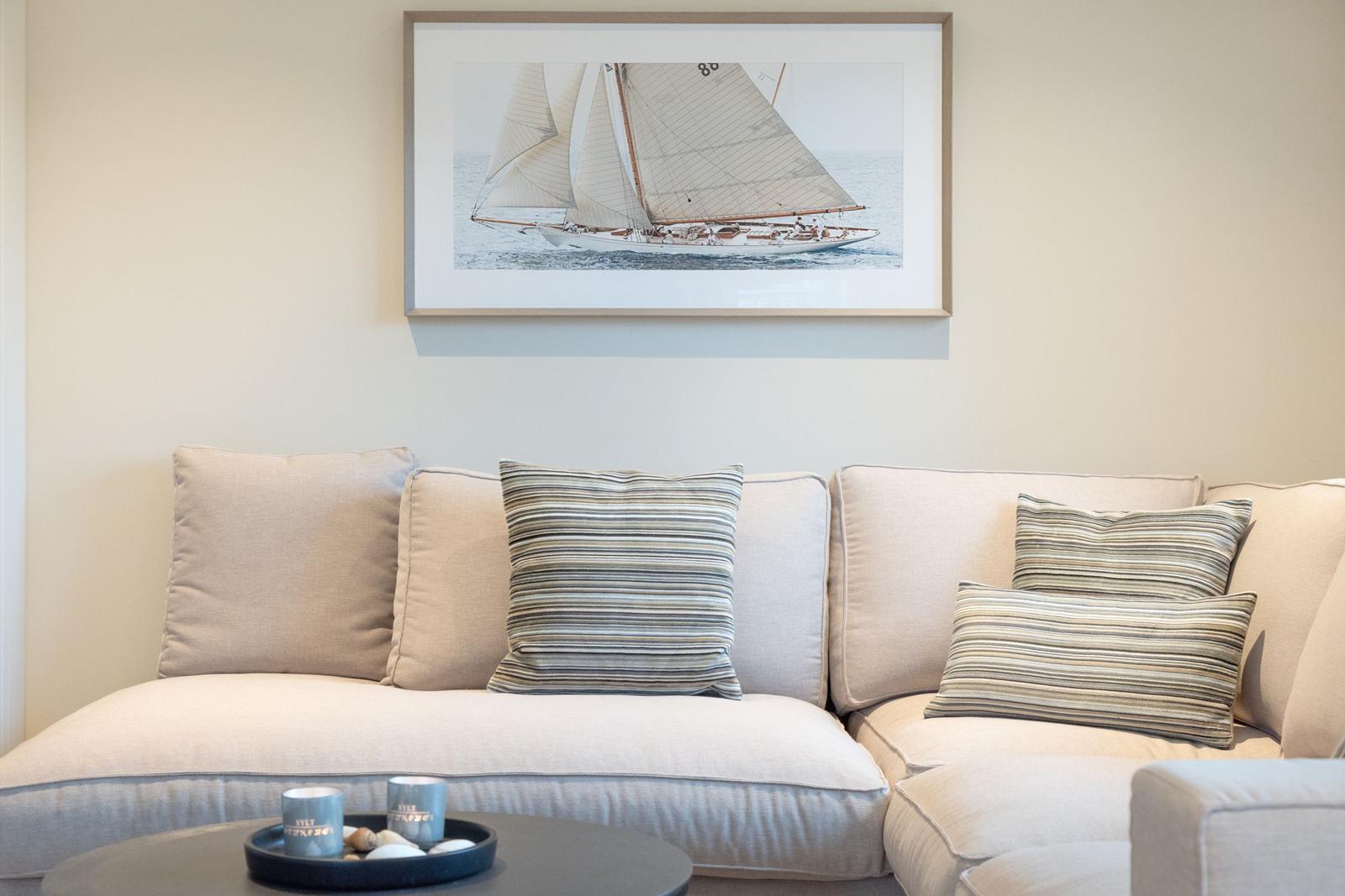Ein Sofa mit Kissen und einem Bild an der Wand.